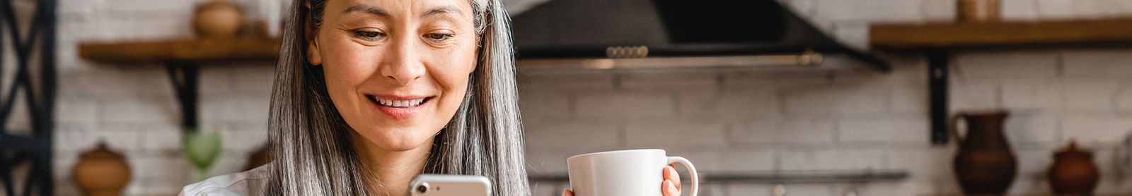 Woman using cell phone in kitchen